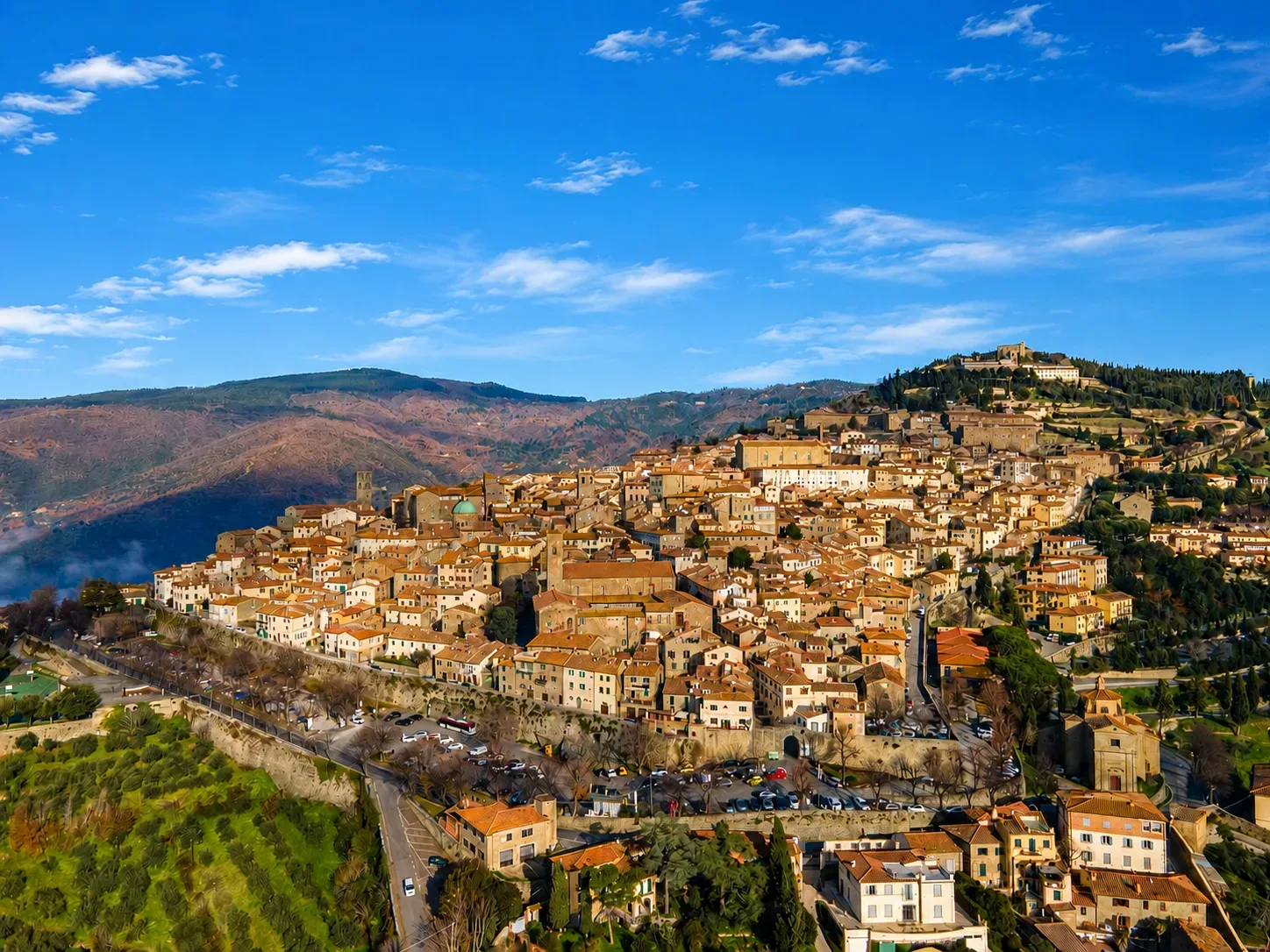 Il borgo medievale di Cortona arroccato sul colle con dietro la sua montagna