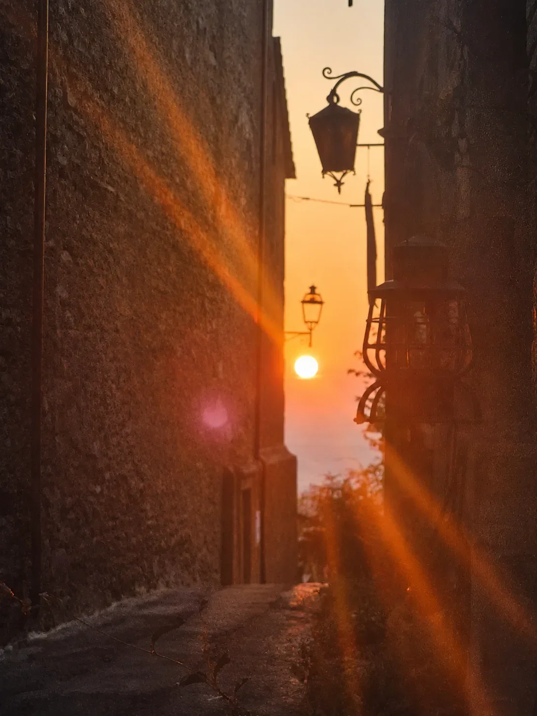 Vicolo di pietra di Cortona illuminato dalla luce calda del tramonto