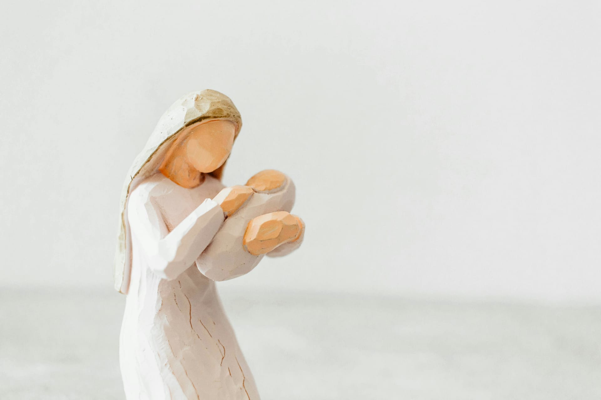 Mani che posano una statuina di pastore in un presepe tradizionale illuminato da luce calda