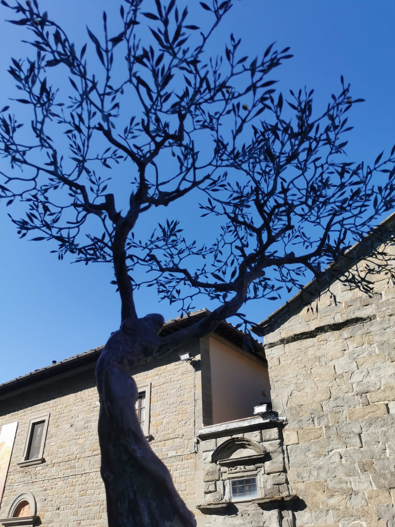 Una persona sale con la borsa della spesa lungo una via lastricata e in pendenza del centro di Cortona