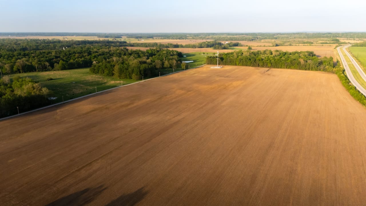 Vista aerea della Val di Chiana con campi coltivati regolari attraversati da un canale rettilineo